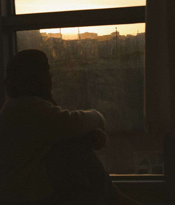Woman performing a gentle yoga stretch in a calm, dark environment with golden light.